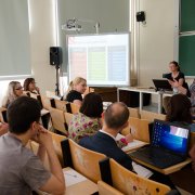 Pracownica Narodowego Centrum Nauki przemawia do uczestników warsztatów dla wnioskodawców, siedzących w ławkach.