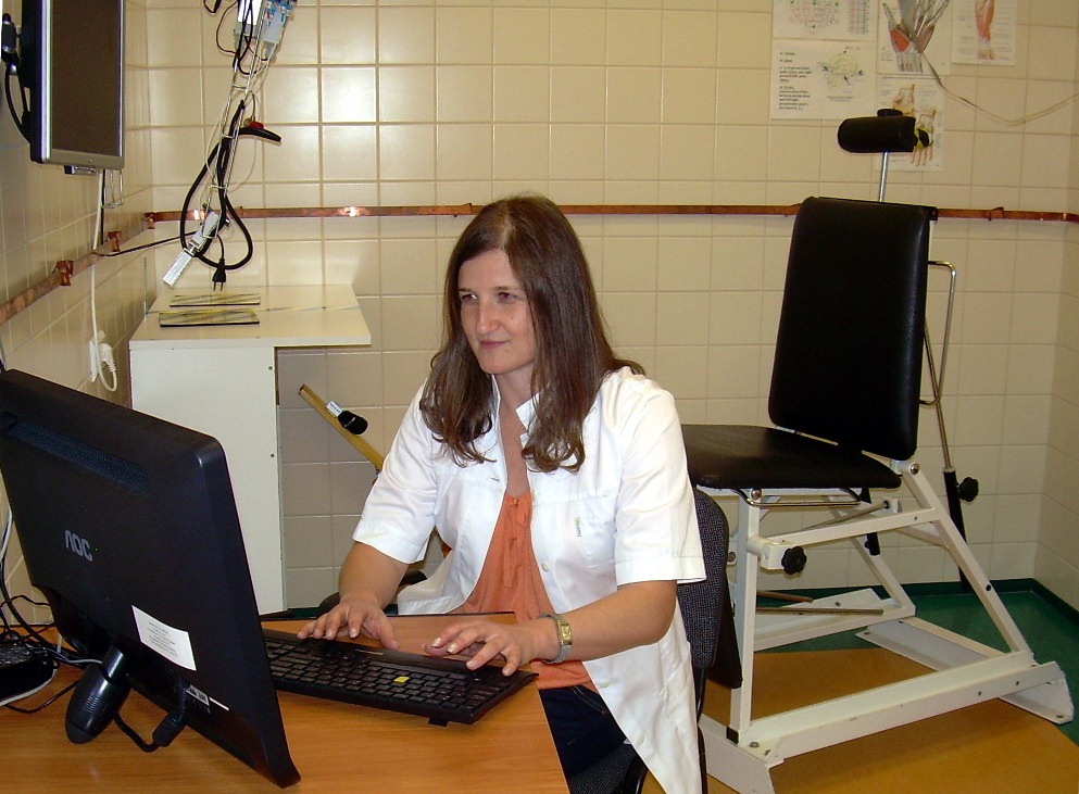 Katarzyna Kisiel-Sajewicz pracuje przy komputerze w laboratorium. W tle widać specjalne krzesło używane w trakcie badań.