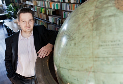 Tomasz Niedzielski pozuje przy dużym globusie
