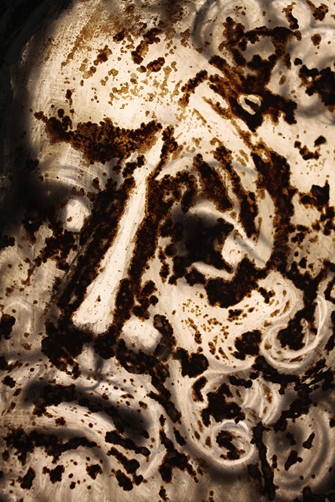 Fragment witraża przedstawiający twarz mężczyzny. Na szkle widać korozję manganową.