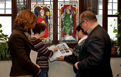 Od lewej: dr Anna Jasińska, dr Małgorzata Walczak, mgr Jolanta Pollesch, dr Paweł Kaszakiewicz Od lewej: dr Anna Jasińska, dr Małgorzata Walczak, mgr Jolanta Pollesch, dr Paweł Kaszakiewicz. Dr Małgorzata Walczak trzyma w rękach księgę. Cała grupa stoi na tle okna z witrażami.