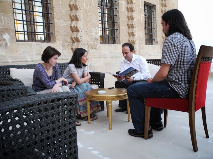 Uczestnicy projektu siedzą przy stole z burmistrzem Diyarbakiru Osmanem Baydemirem