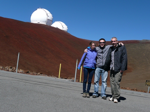 Doktor Michał Drahus (w środku) z żoną Agnieszką i bliskim współpracownikiem dr. hab. Wacławem Waniakiem w obserwatorium Mauna Kea. W tle kopuły teleskopów Kecka, które wykorzystywane są w projekcie.