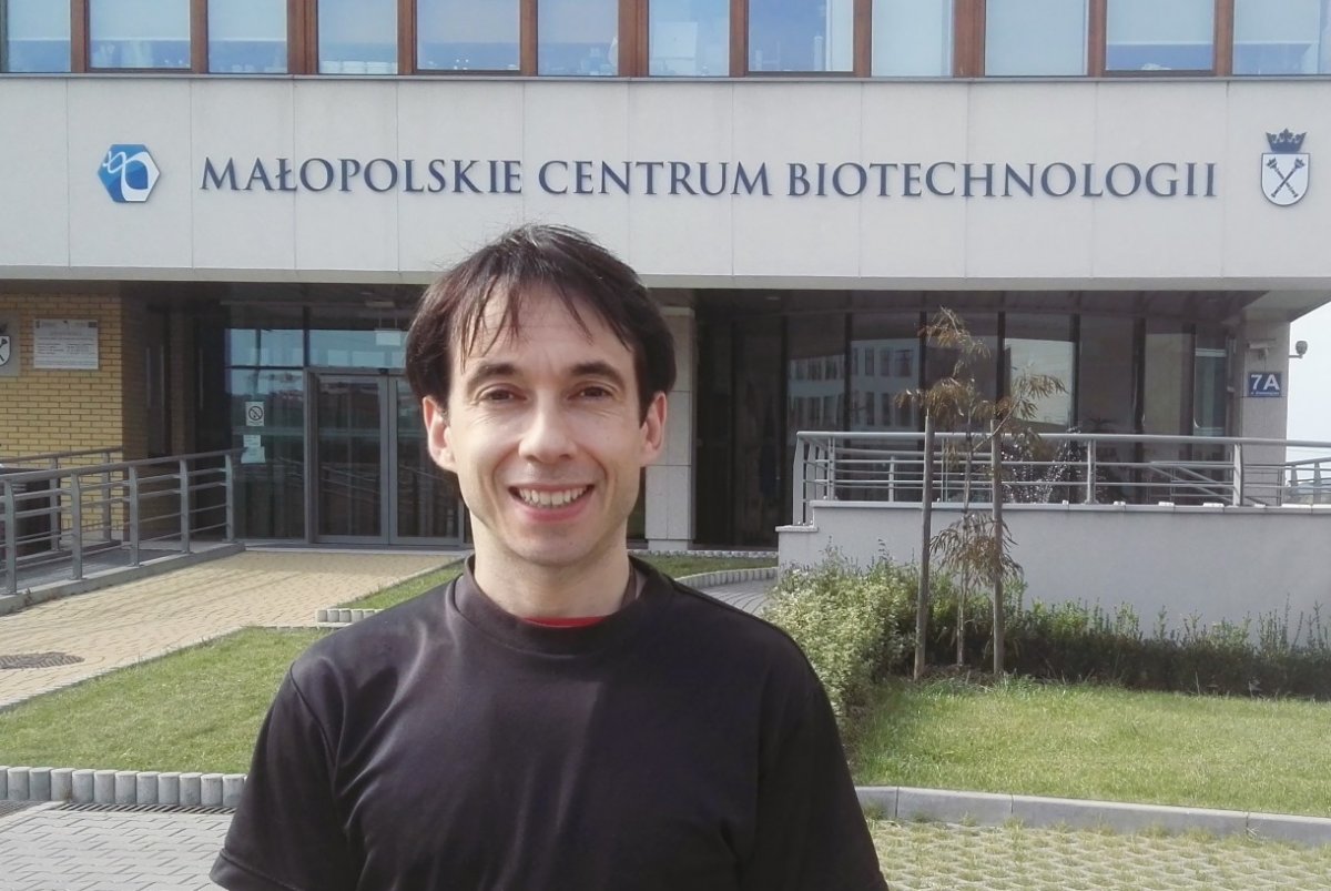Jonathan Gardiner Heddle pozuje na tle budynku Małopolskiego Centrum Biotechnologii Uniwersytetu Jagiellońskiego