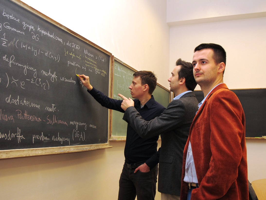 Doktor Piotr Nowak z dwoma studentami przy tablicy